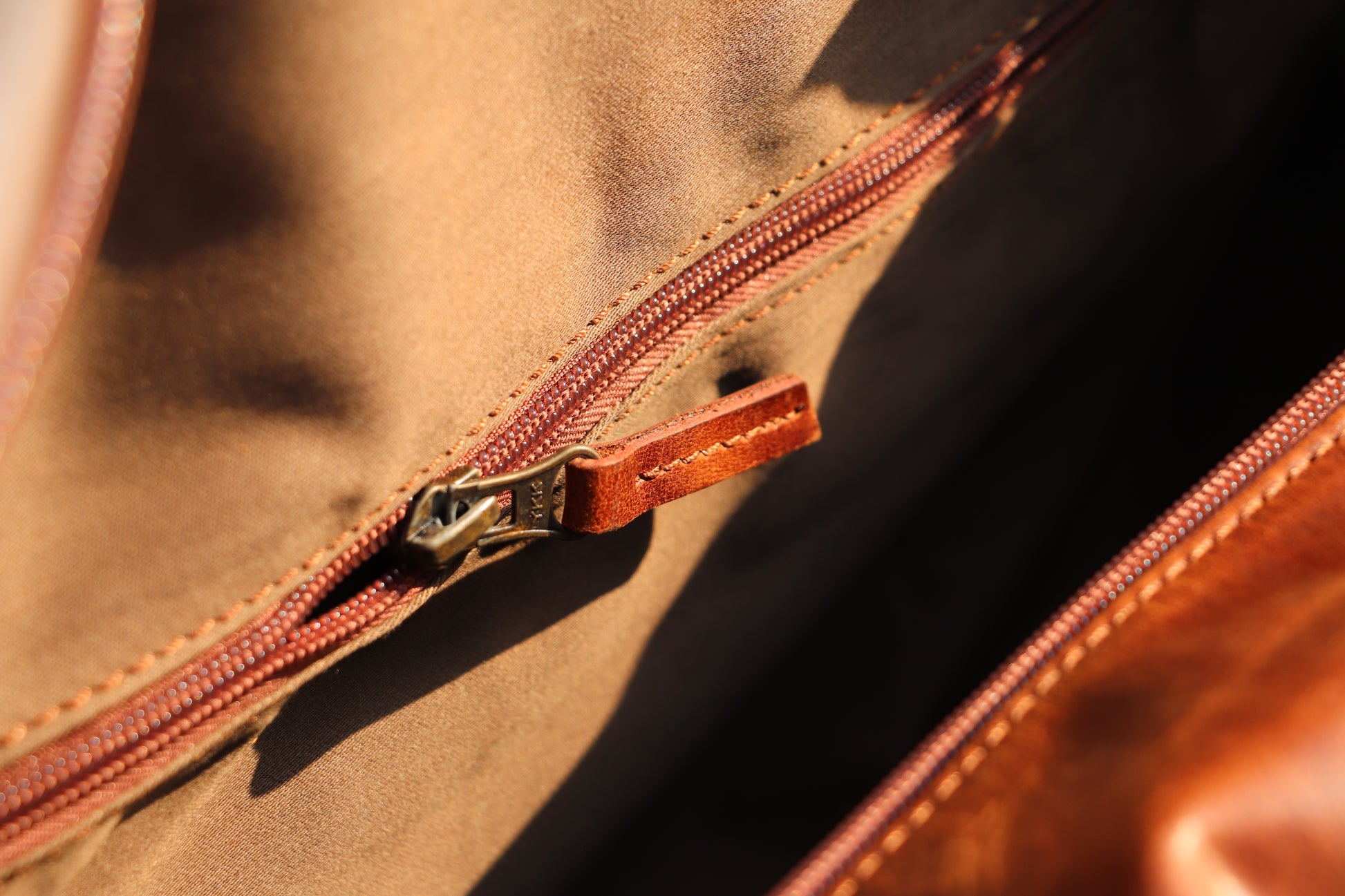 Close-up of a brown leather bag with a zipper