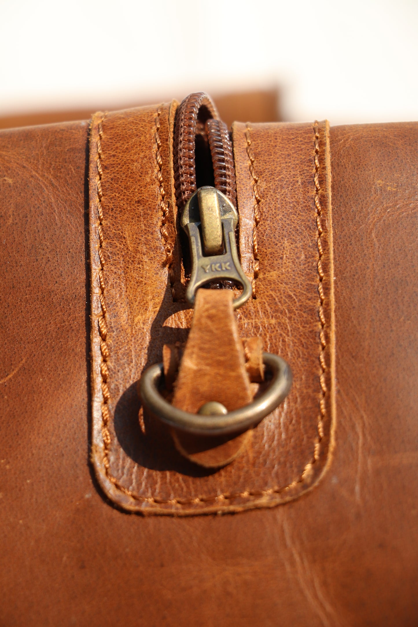 Close-up of a brown leather bag with a gold zipper.