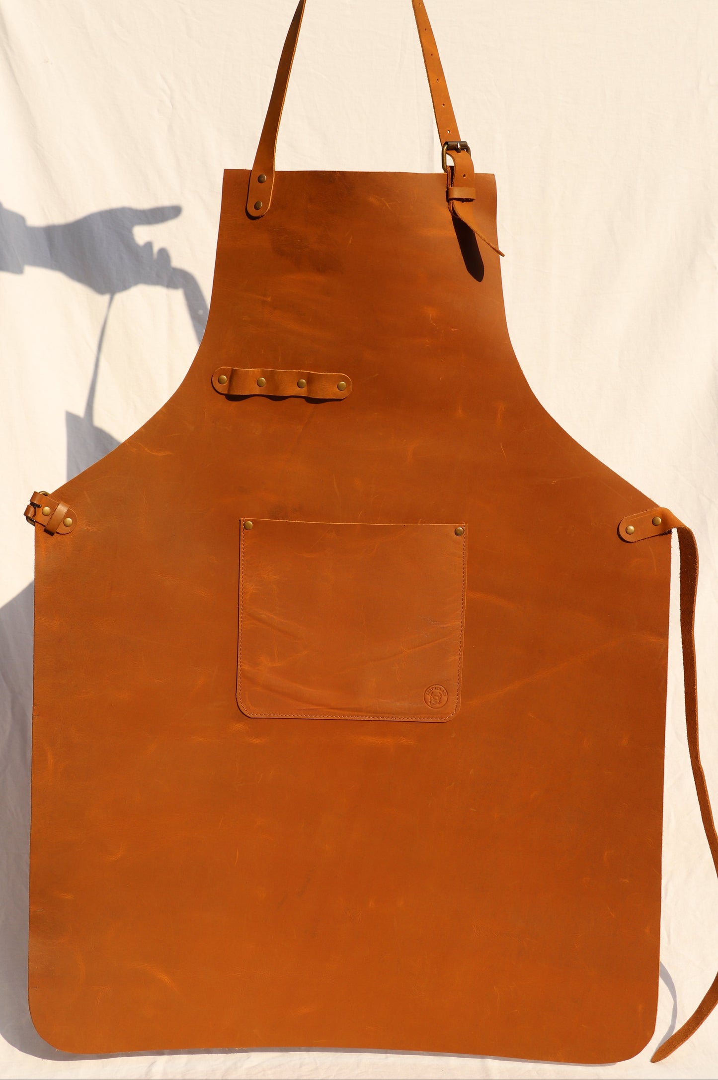Brown leather apron held by a person on a light background
