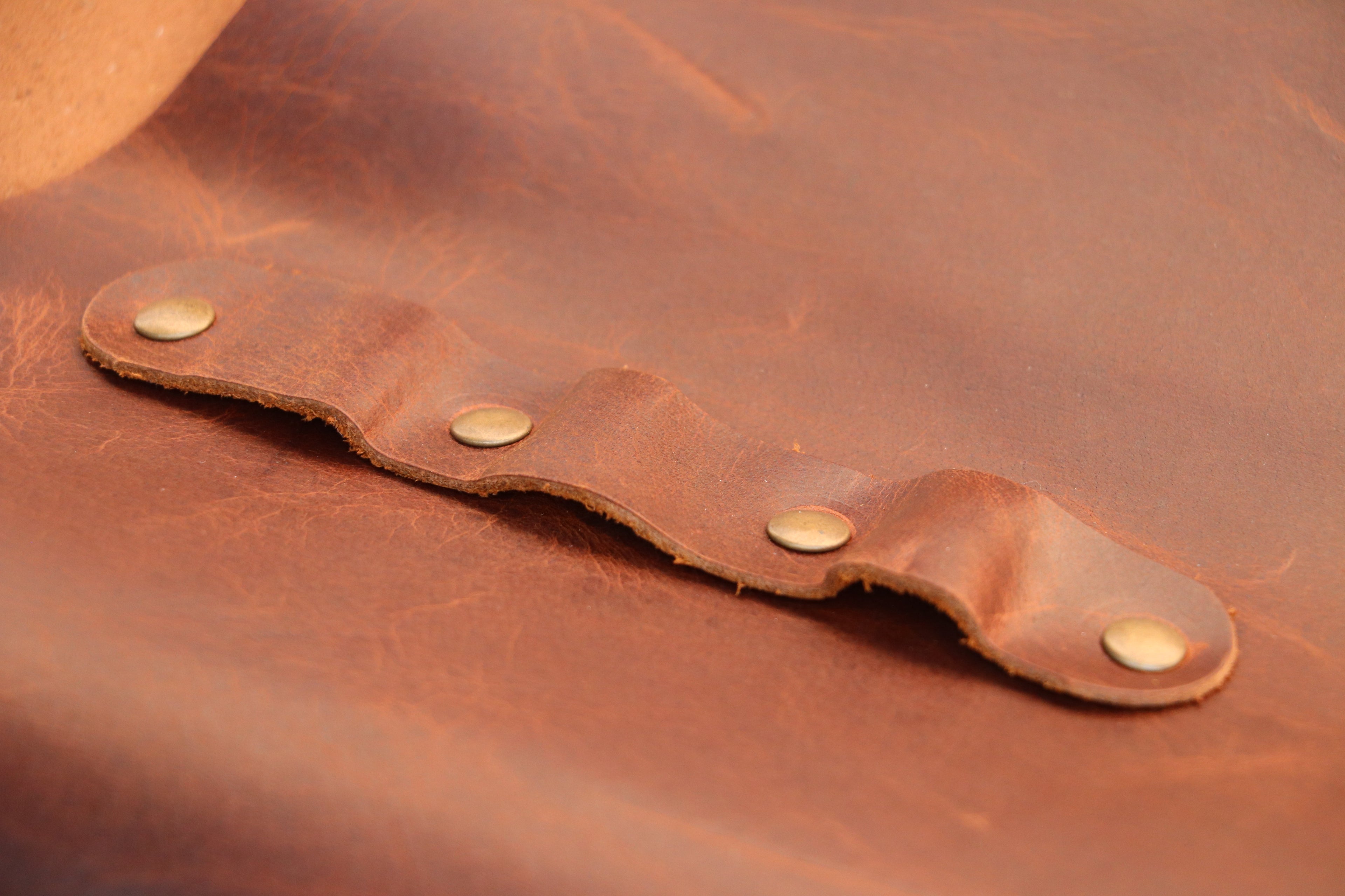 Close-up of a brown leather apron with metal studs